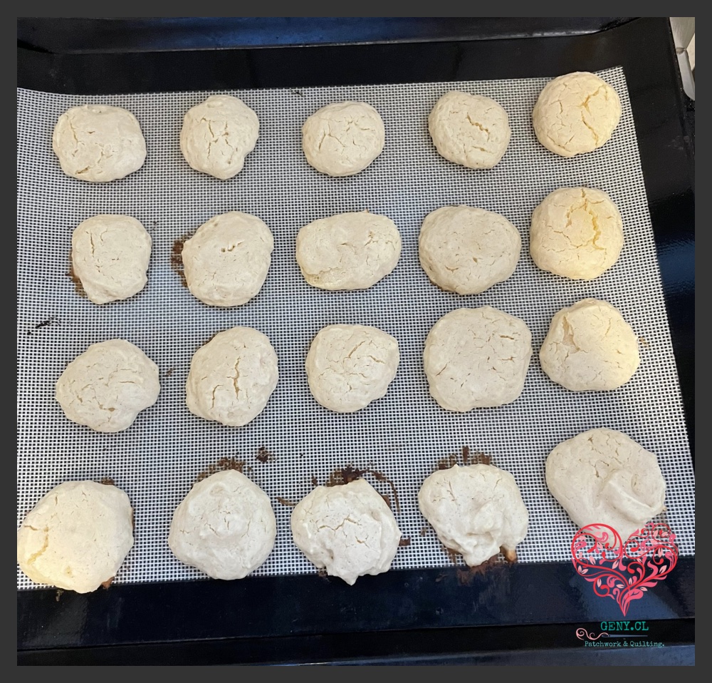 Galletas caseras de queso recién horneadas sobre una bandeja con malla, de aspecto rústico y color claro.