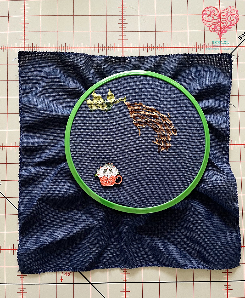 bordado en tela azul con bastidor verde y needleminder de navidad. Avances de un proyecto de punto cruz