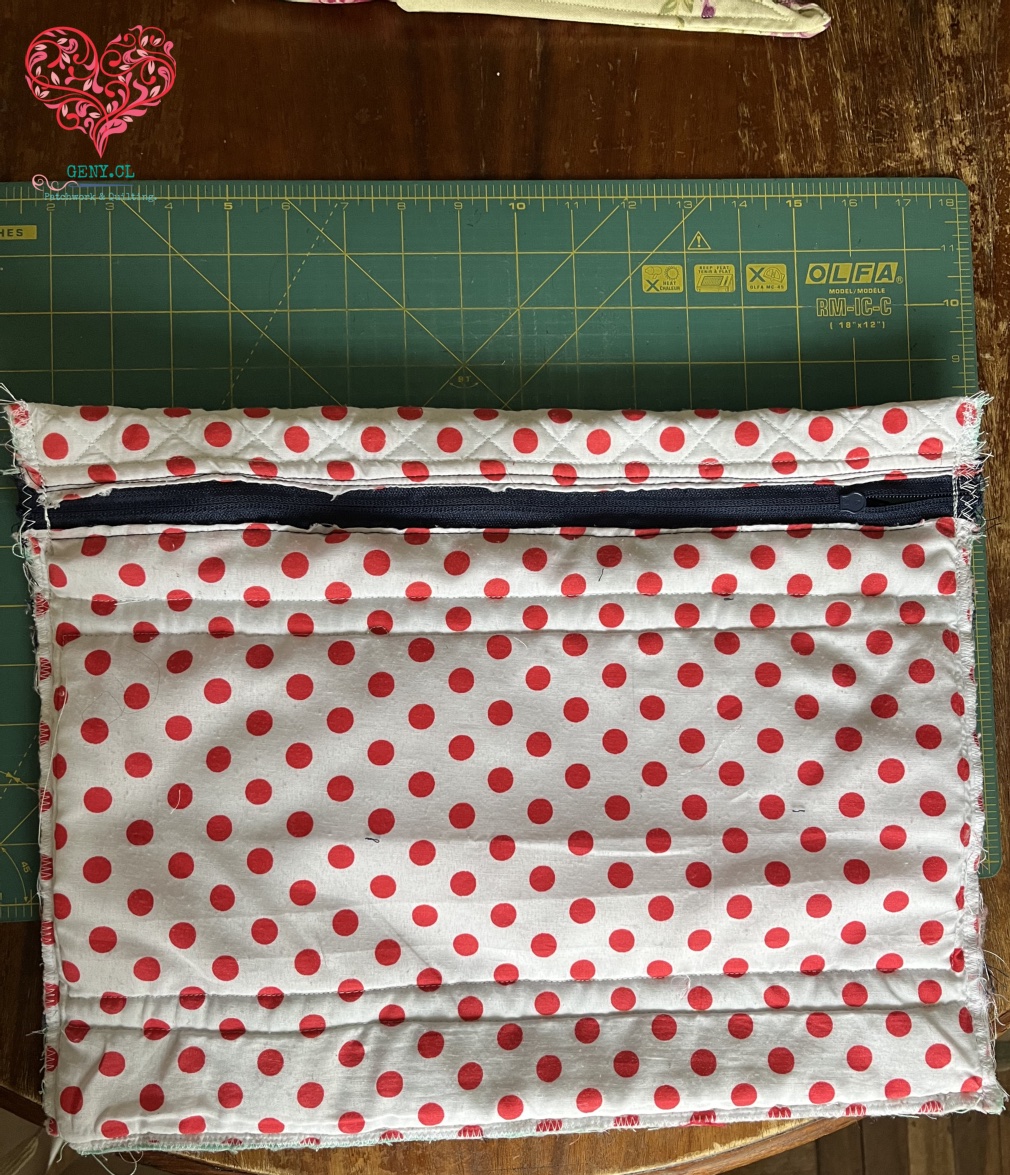 Así quedo el bolso. con el cierre cosido, entre el genero de polka dots rojos.