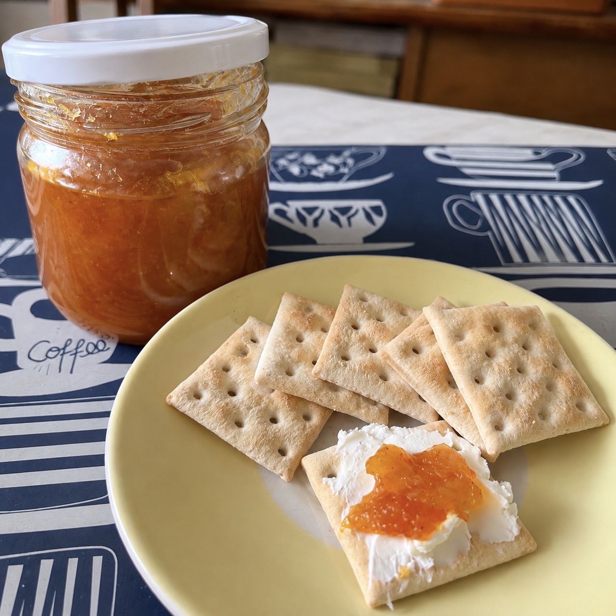 Mermelada de naranja casera servida con queso crema y galletas saladas.