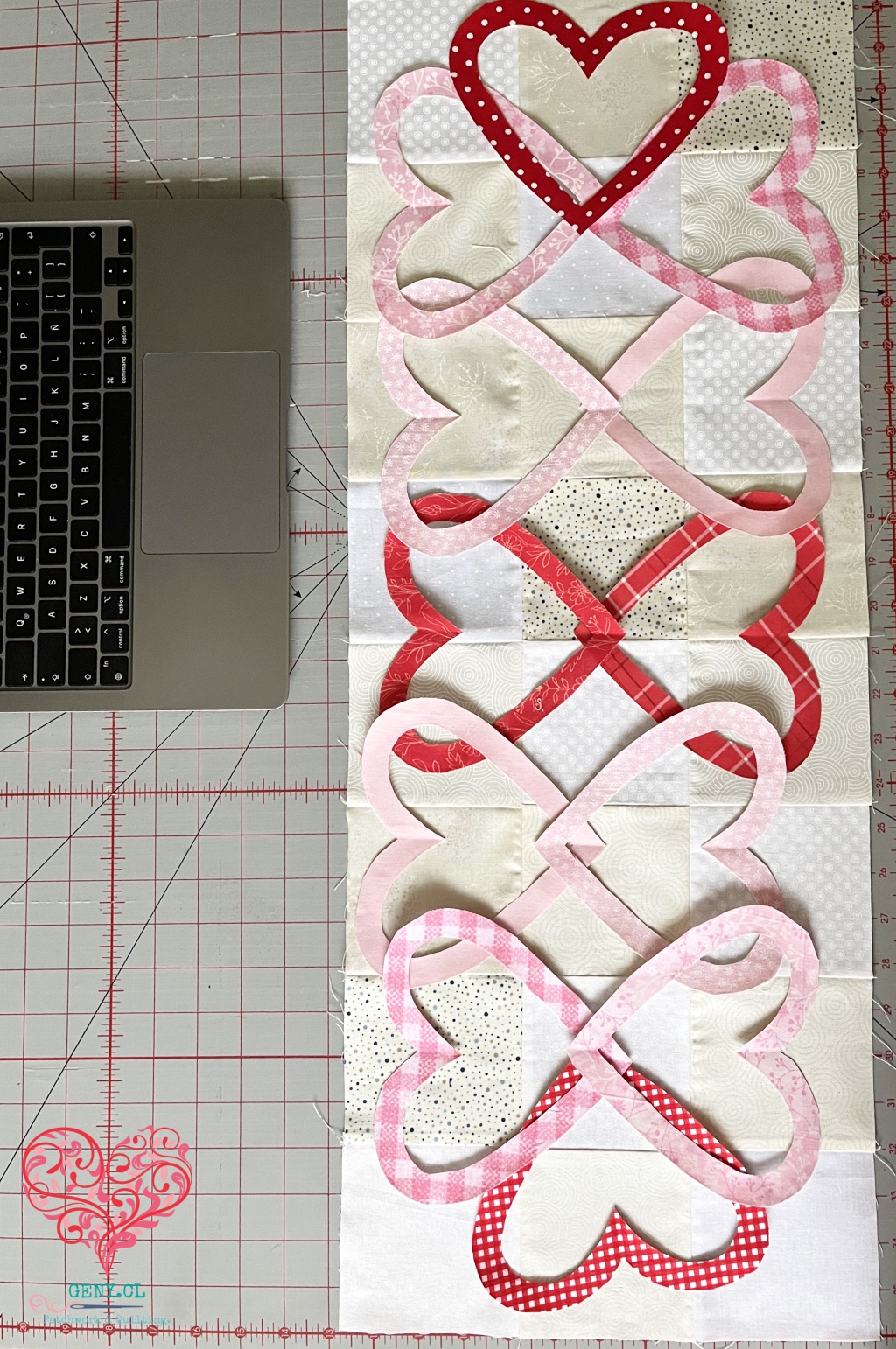 Corazones rojos y rosados entrelazados como eslabones sobre el fondo de patchwork de Hearts Entwined de Art to Heart.