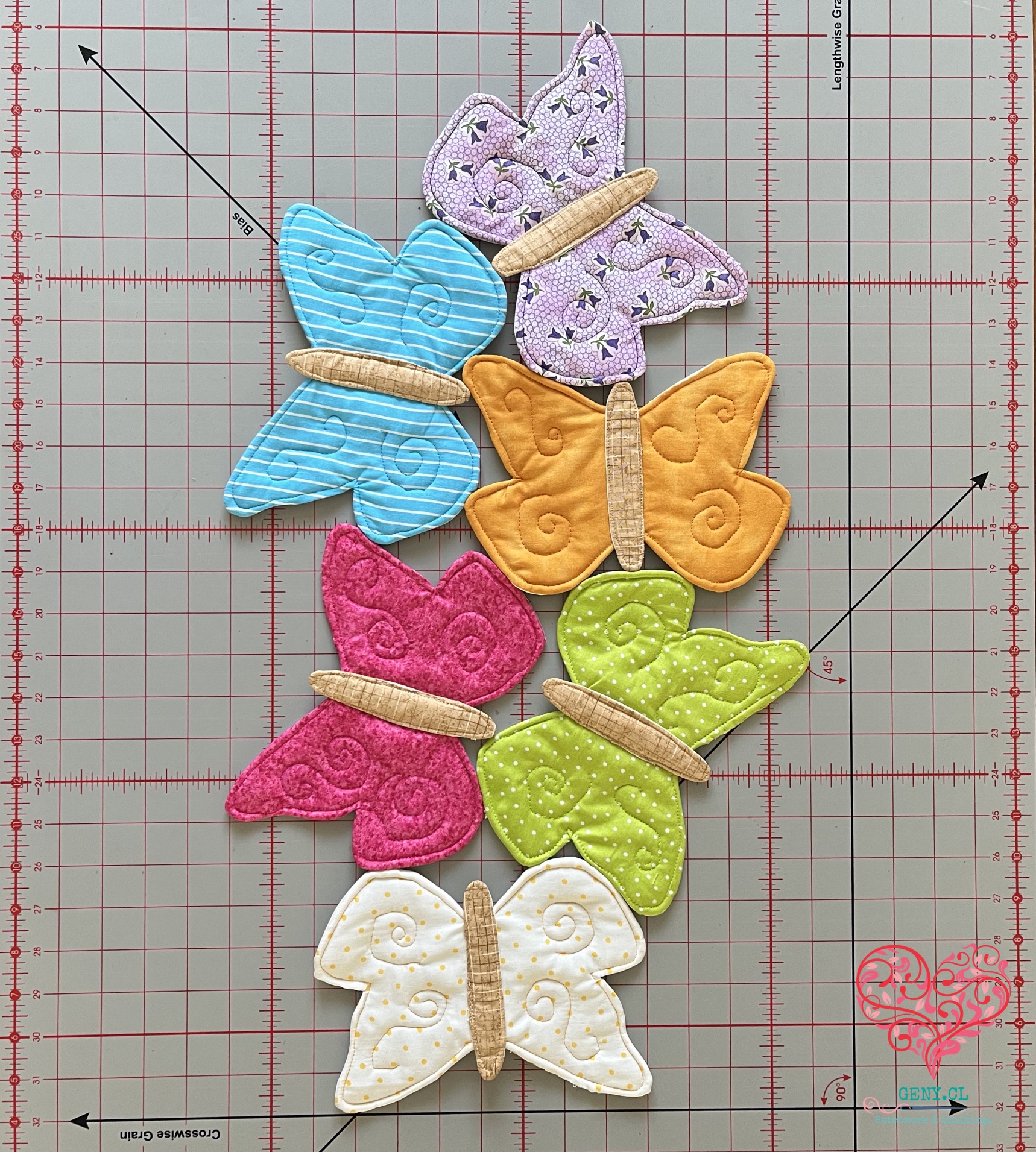 Camino de mesa de seis mariposas acolchadas en telas de colores, diseñado por Nancy Halvorsen y confeccionado en patchwork.