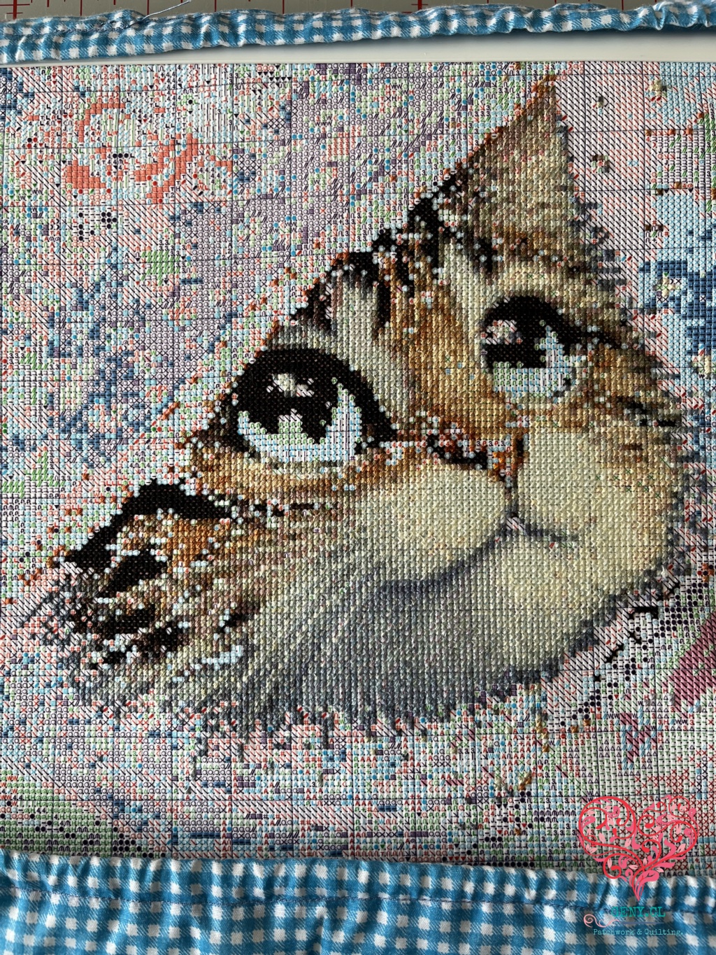 Avance del bordado de cobertura completa Gata Mágica de Painting Fairy, con el rostro de la gata parcialmente bordado y el verde de sus ojos pendiente.