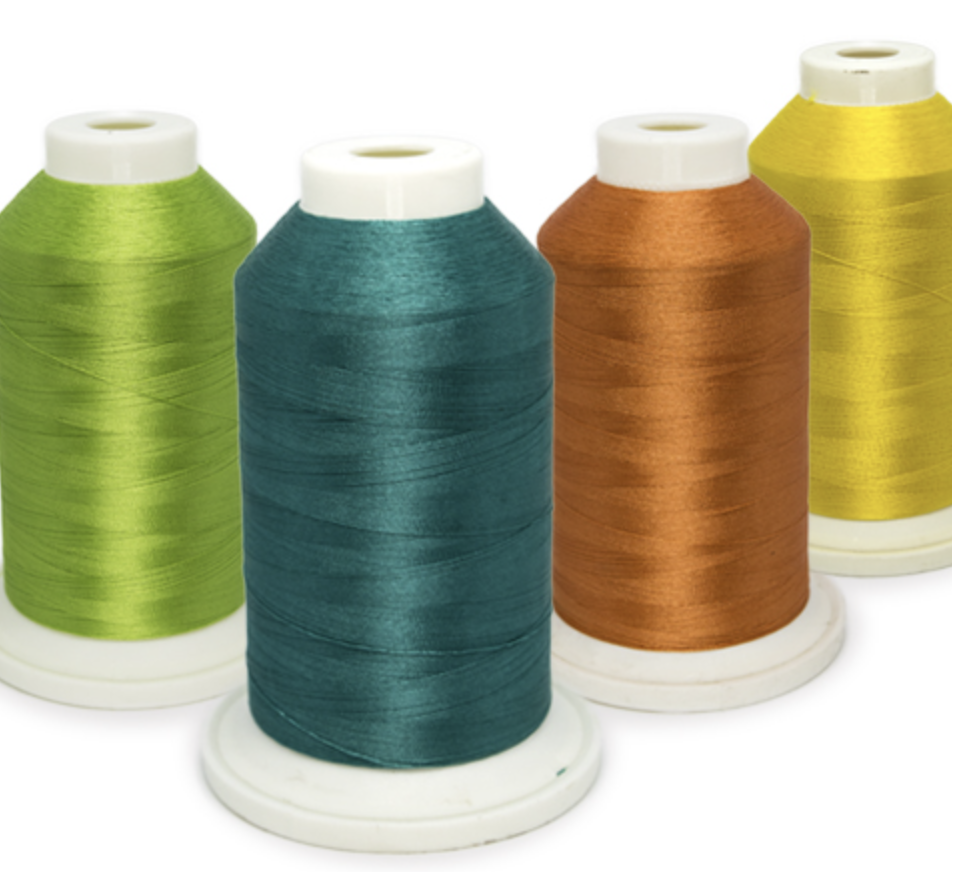 Cuatro conos de hilo Ghost en colores verde, turquesa, cobre y amarillo, utilizados como opción para acolchado en quilting.