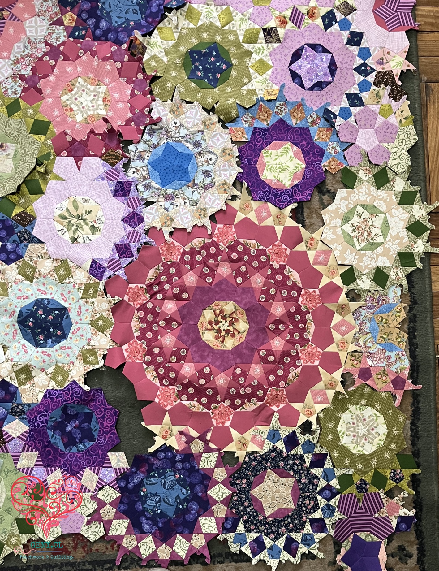 Rosetas de patchwork del Passacaglia Quilt distribuidas sobre una alfombra para comprobar su posición antes del montaje con English Paper Piecing.