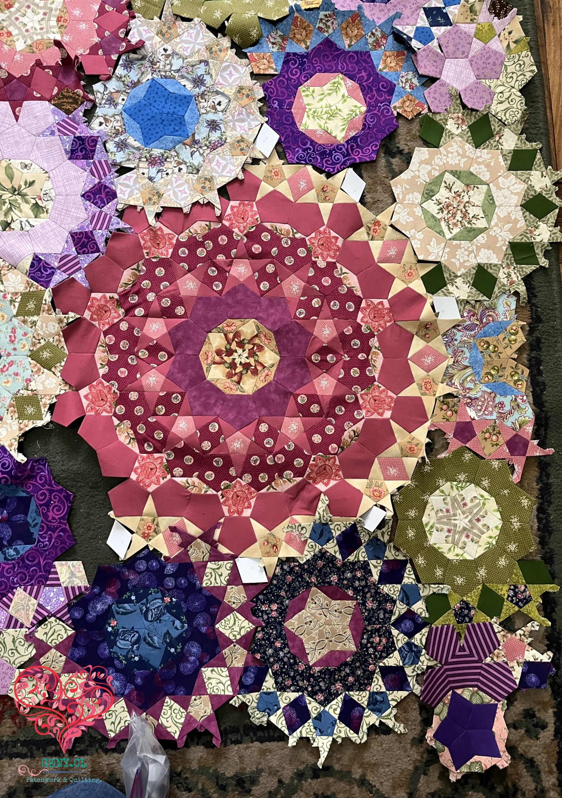 Detalle del Passacaglia Quilt con plantillas de papel de los rombos A colocadas provisionalmente entre las rosetas de English Paper Piecing.