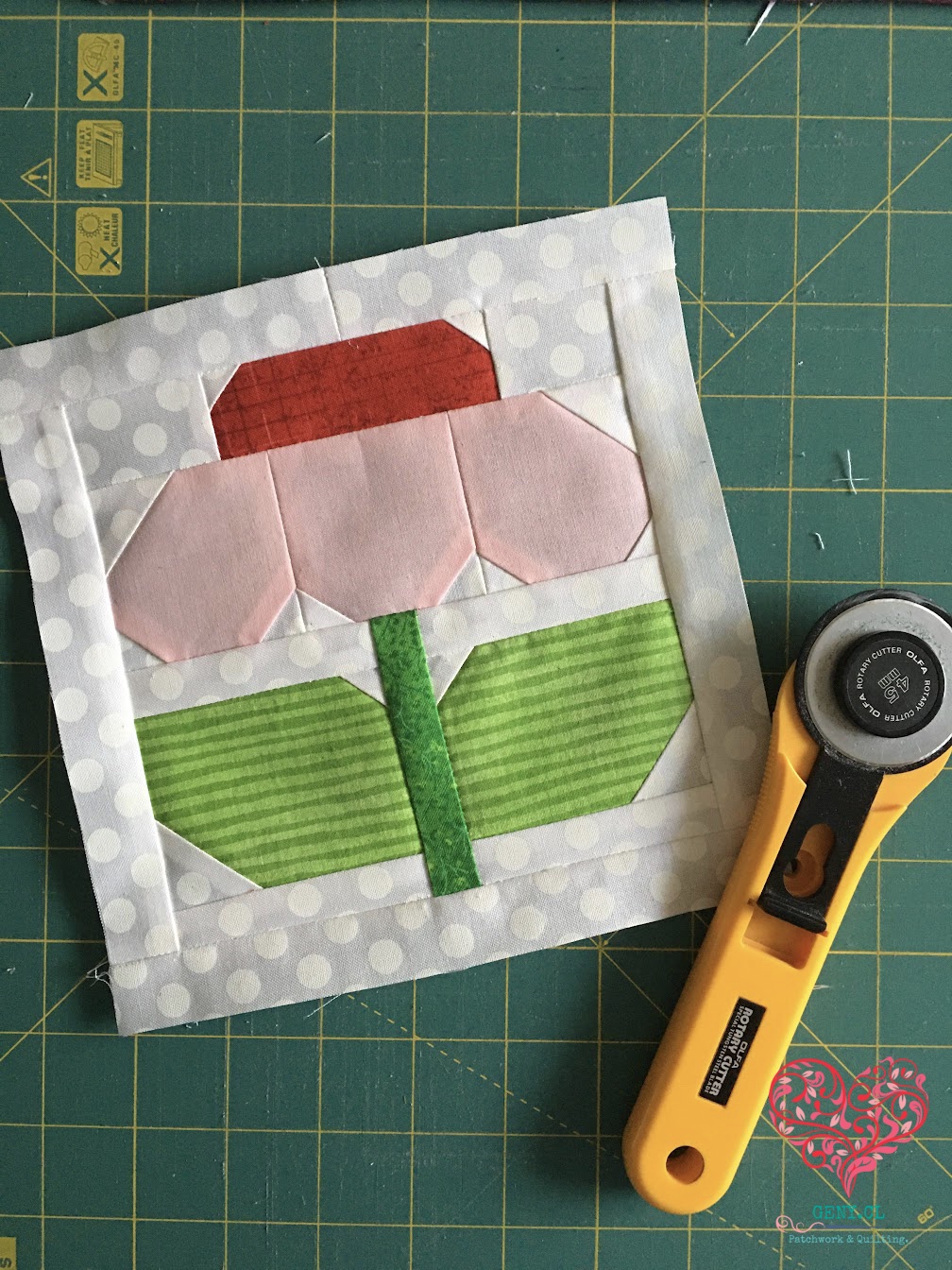 Bloque de patchwork con una flor sobre una base de corte, antes del quilting.
