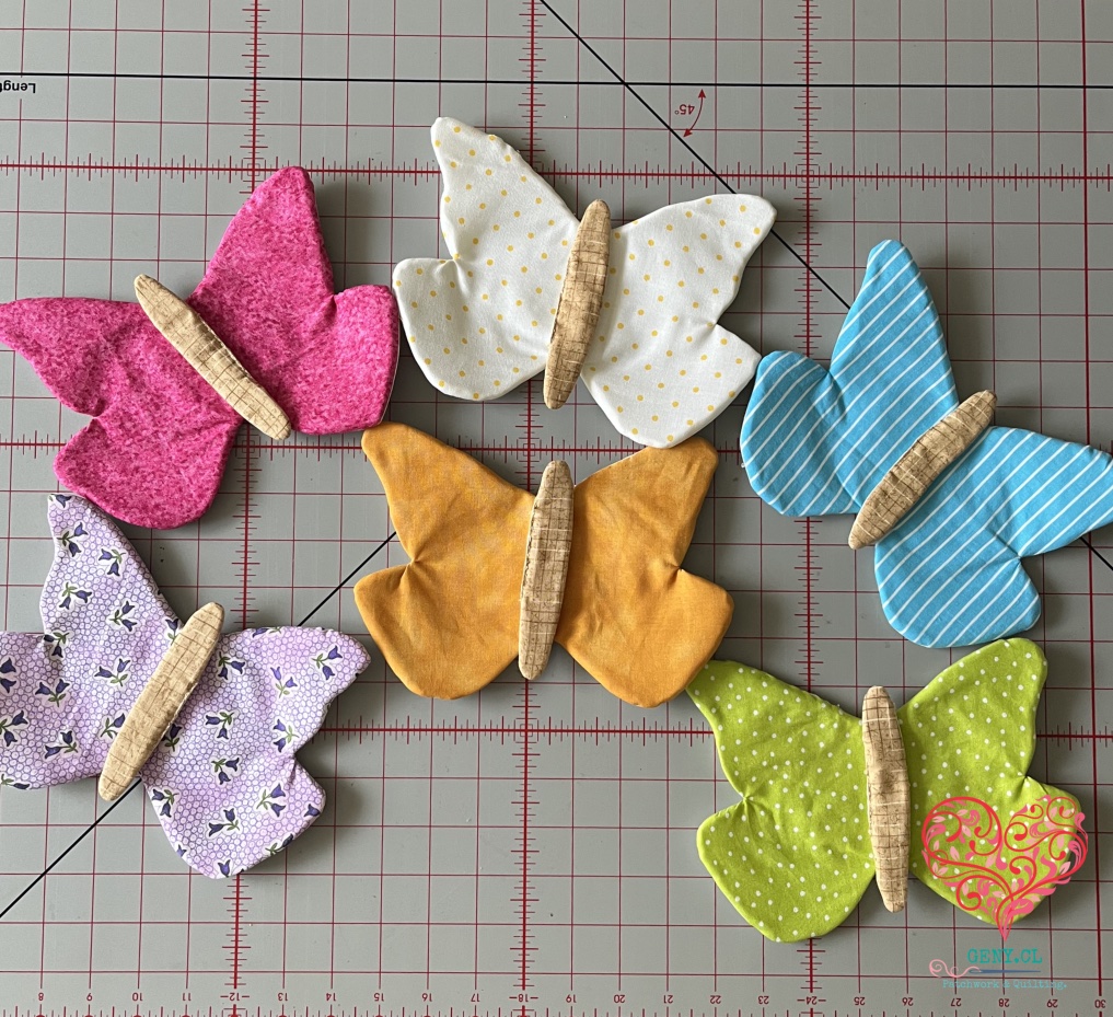 Seis mariposas de patchwork en fucsia, blanco, calipso, lila, naranja y verde, antes de acolchar los espirales.