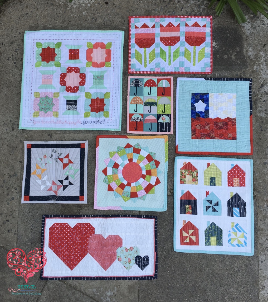 Colección de mini quilts de patchwork scrappy fotografiados juntos en el jardín.
